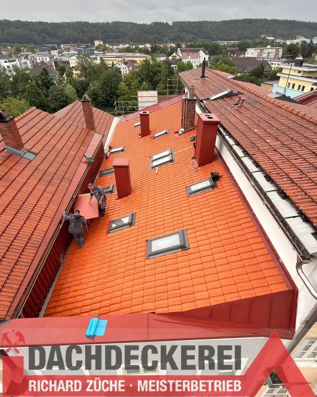Dachdecker bei Arbeiten an einem Ziegeldach mit Gauben